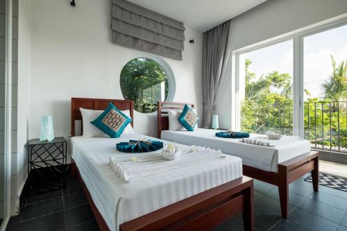 two beds in a room with a large window at Pippali Boutique Hotel in Kampot