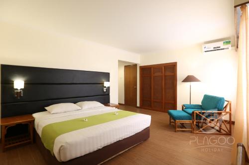 um quarto de hotel com uma cama grande e uma cadeira em Plagoo Holiday Hotel em Nusa Dua