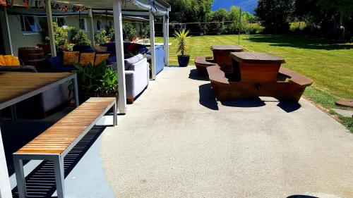 a patio with three benches and a table at Happy Apple Backpackers in Motueka