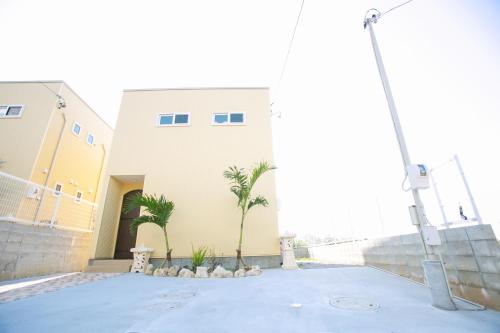 a building with palm trees in front of it at Irie House Fuchaku in Onna