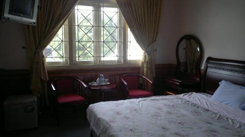 a bedroom with a bed and two chairs and a window at Hue Railway Hotel in Hue