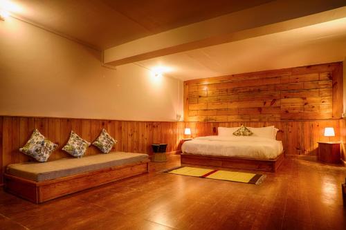 a bedroom with a bed and a bench in it at Enchanted Hills Farmstay in Mukteswar