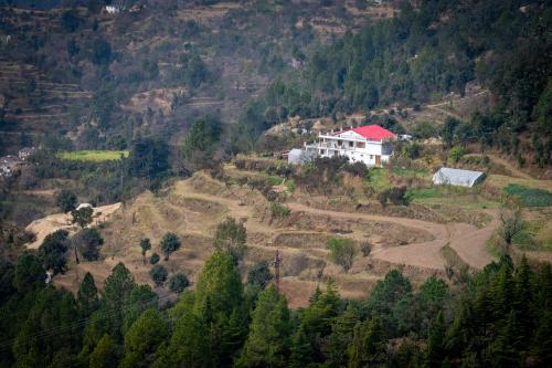 a house on top of a hill with trees at Enchanted Hills Farmstay in Mukteswar