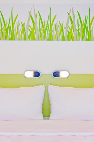a bed with two pillows and a green wall at Ibis budget Lorient Caudan in Caudan