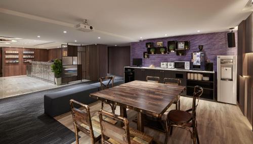 a kitchen with a wooden table and chairs and a refrigerator at Muzik Hotel - Ximen Station Branch in Taipei