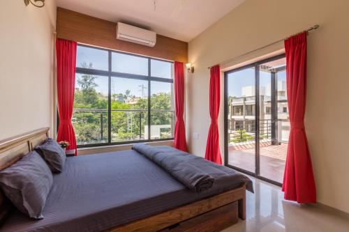 - une chambre avec un lit doté de rideaux rouges et une grande fenêtre dans l'établissement StayVista's Greenwoods Villa 6 - City-Center Villa with Private Pool, Terrace, Lift & Ping-Pong Table, à Lonavala