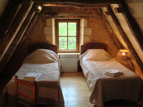 two beds in a attic room with a window at Maison Milou in Beynac-et-Cazenac