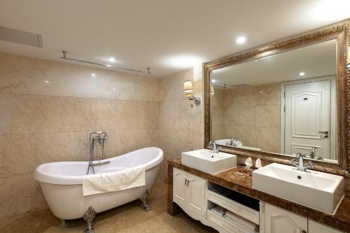 baño con bañera, 2 lavabos y espejo grande en Guilin Bravo Hotel, en Guilin