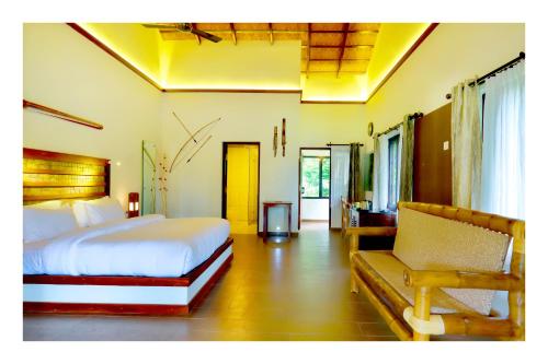 1 dormitorio con cama y sofá en Vayal Veedu - Luxury Farm Villas by the woods, en Muthanga