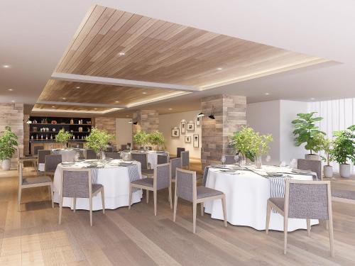 a dining room with white tables and chairs at Oriental Hotel Fukuoka Hakata Station in Fukuoka