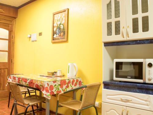 een keuken met een tafel met stoelen en een magnetron bij Hostal Inthalassa Caldera in Caldera