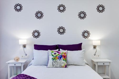 1 dormitorio con 1 cama blanca con reloj en la pared en El Galeón, en Playa Blanca