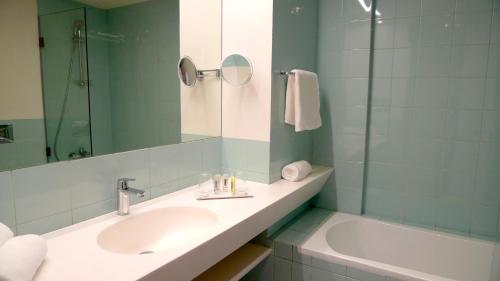 a bathroom with a sink and a tub and a mirror at Bossa Nova Beirut Hotel in Beirut