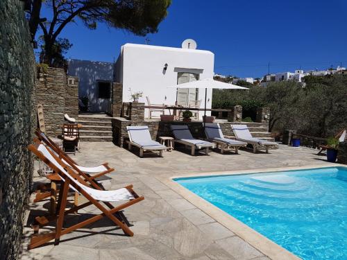 een villa met een zwembad en stoelen en een huis bij Andromeda in Exámbela