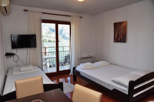a room with two beds and a table and a balcony at Apartment Lima in Kotor