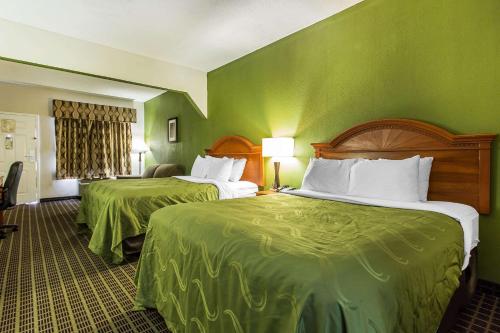 two beds in a hotel room with green walls at Quality Inn & Suites Orangeburg in Orangeburg
