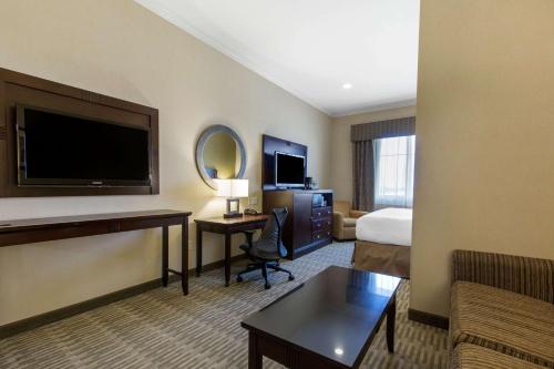 a hotel room with a bed and a desk with a television at The Oaks Hotel & Suites in Paso Robles