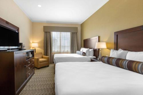 a hotel room with two beds and a flat screen tv at The Oaks Hotel & Suites in Paso Robles