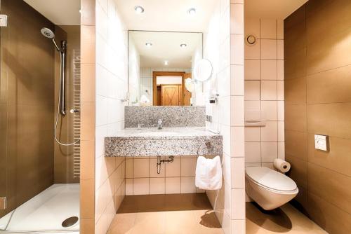 a bathroom with a sink and a toilet and a mirror at Hotel Landhaus Feckl in Böblingen