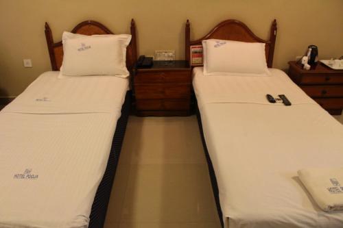 two beds in a room with white sheets at Hotel Pooja International in Dāvangere