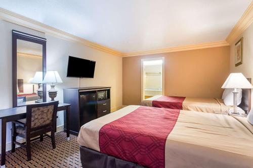 a hotel room with two beds and a desk and a television at Parkway Inn of Birmingham in Birmingham