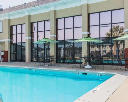 a pool with tables and umbrellas in front of a building at Quality Inn & Suites North Montgomery in Montgomery