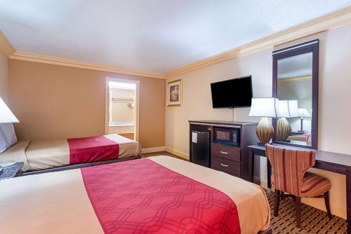 a hotel room with two beds and a desk and a television at Parkway Inn of Birmingham in Birmingham