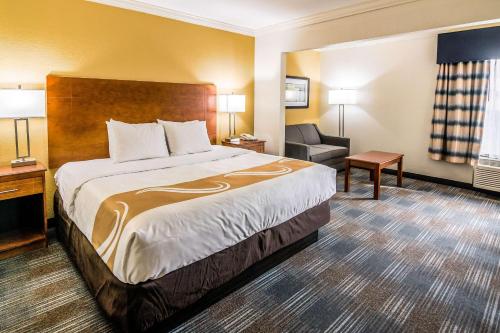 a hotel room with a large bed and a chair at Quality Inn Alexander City in Alexander City