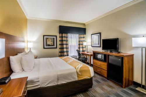 a hotel room with a bed and a flat screen tv at Quality Inn Alexander City in Alexander City