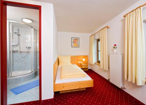 um pequeno quarto com uma cama e um chuveiro em Hotel Reitlwirt em Brixen im Thale