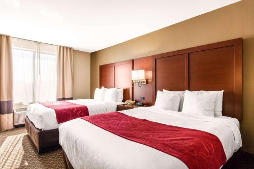 a hotel room with two beds with red sheets at Comfort Suites Tuscaloosa near University in Tuscaloosa
