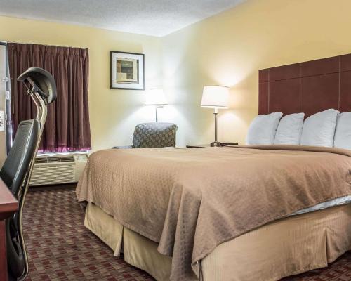 a hotel room with a large bed and a chair at Quality Inn in Madison