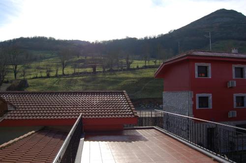 a balcony of a red building with a mountain in the background at Hotel - Apartamentos Peña Santa in Onís