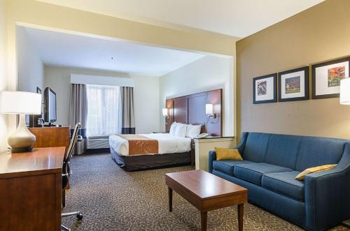 een hotelkamer met een bed en een blauwe bank bij Quality Suites in Springdale