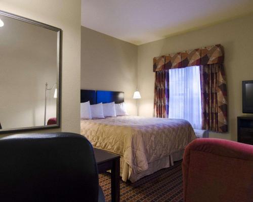 a hotel room with a bed and a mirror at Affordable Suites of America Rogers - Bentonville in Rogers