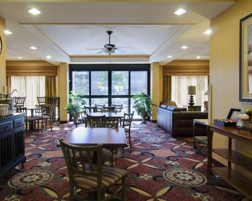 a dining room with tables and chairs and a living room at Affordable Suites of America Rogers - Bentonville in Rogers