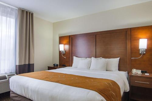 a hotel room with a large bed with a wooden headboard at Quality Suites Springdale West I-49 in Springdale