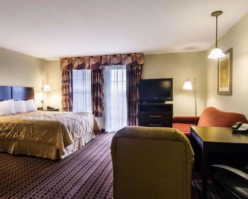 um quarto de hotel com uma cama e uma televisão de ecrã plano em Affordable Suites of America Rogers - Bentonville em Rogers