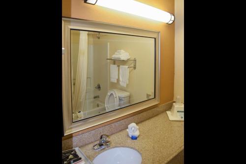 a bathroom with a sink and a mirror and a toilet at American Inn & Suites West Memphis in West Memphis