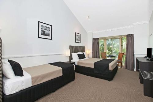 a hotel room with two beds and a desk at Comfort Inn & Apartments Northgate Airport in Brisbane