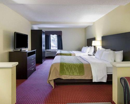a hotel room with two beds and a flat screen tv at Quality Inn & Suites Little Rock West in Little Rock
