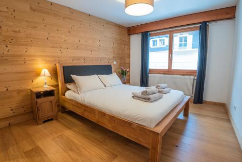 ein Schlafzimmer mit einem Bett mit einer Holzwand in der Unterkunft Mintaka Apartment - Chamonix in Chamonix-Mont-Blanc