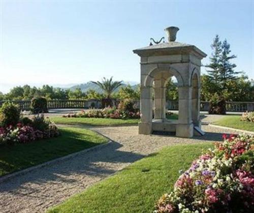 a stone arch in a park with flowers at Hôtel Adour in Pau