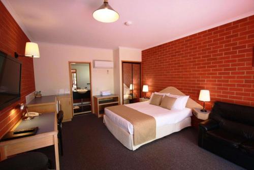 a hotel room with a bed and a brick wall at Comfort Inn Lady Augusta in Swan Hill