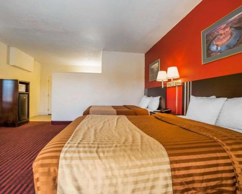 two beds in a hotel room with red walls at Rodeway Inn at Lake Powell in Page