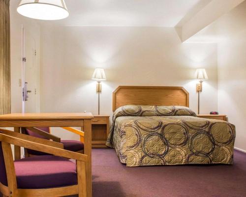 a bedroom with a bed and a table and a chair at Rodeway Inn Silver Creek Inn in Taylor