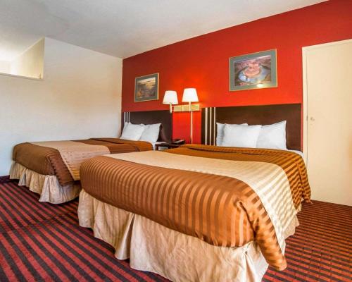 two beds in a hotel room with red walls at Rodeway Inn at Lake Powell in Page