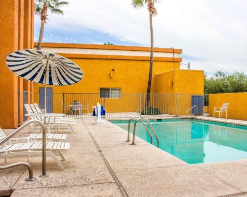 a pool with chairs and an umbrella next to a building at Quality Inn - Tucson Airport in Tucson