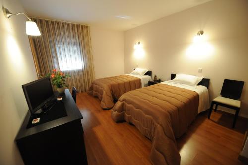 a hotel room with two beds and a flat screen tv at Senhor dos Perdoes Alojamento Local in Ribeirão
