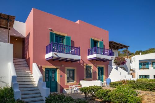 a pink house with blue balconies and stairs at Nefeli Hotel Leros in Agia Marina